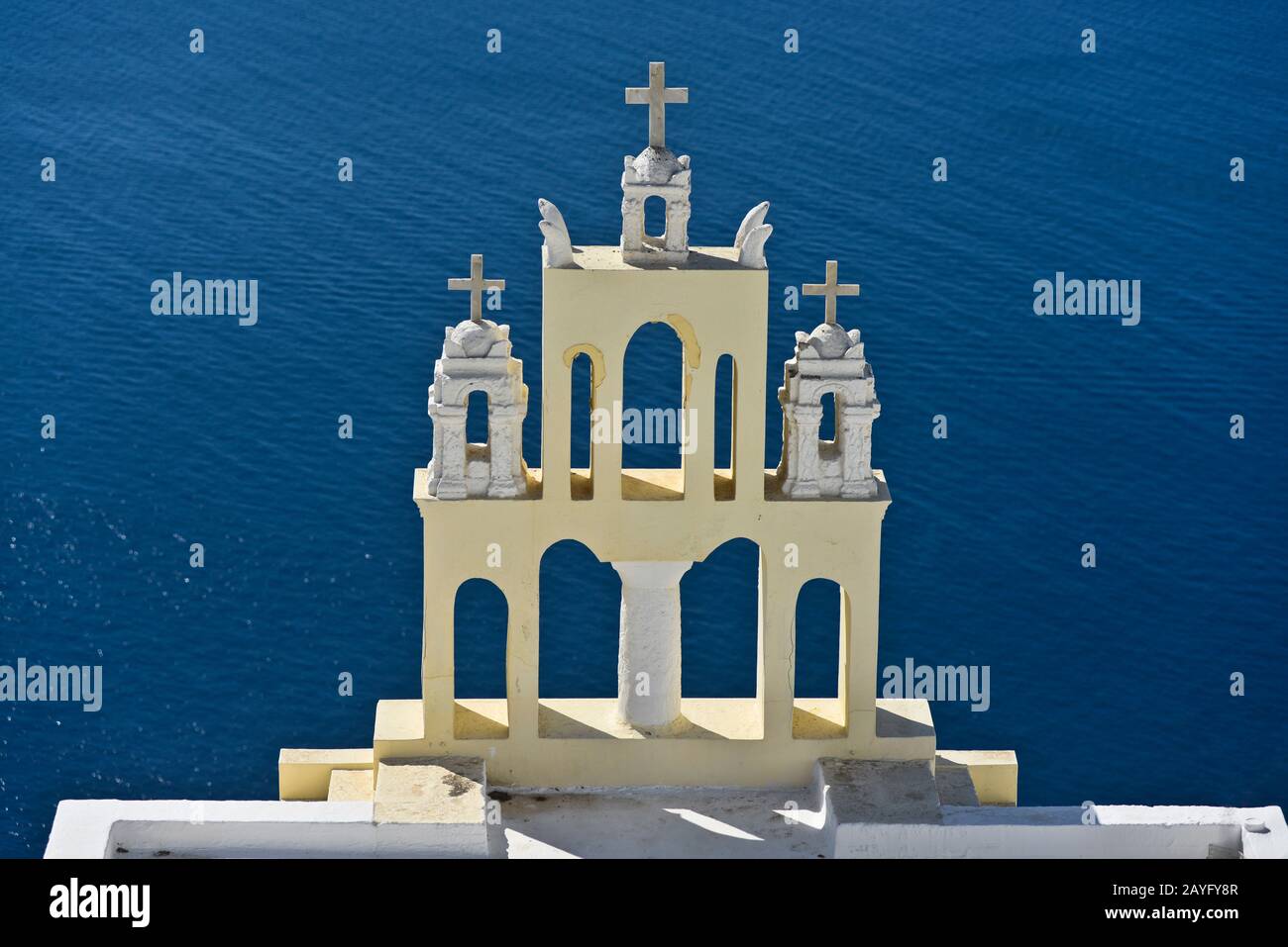 Yellow church bell tower on the edge of the town of Fira on Santorini island, Greece. Stock Photo