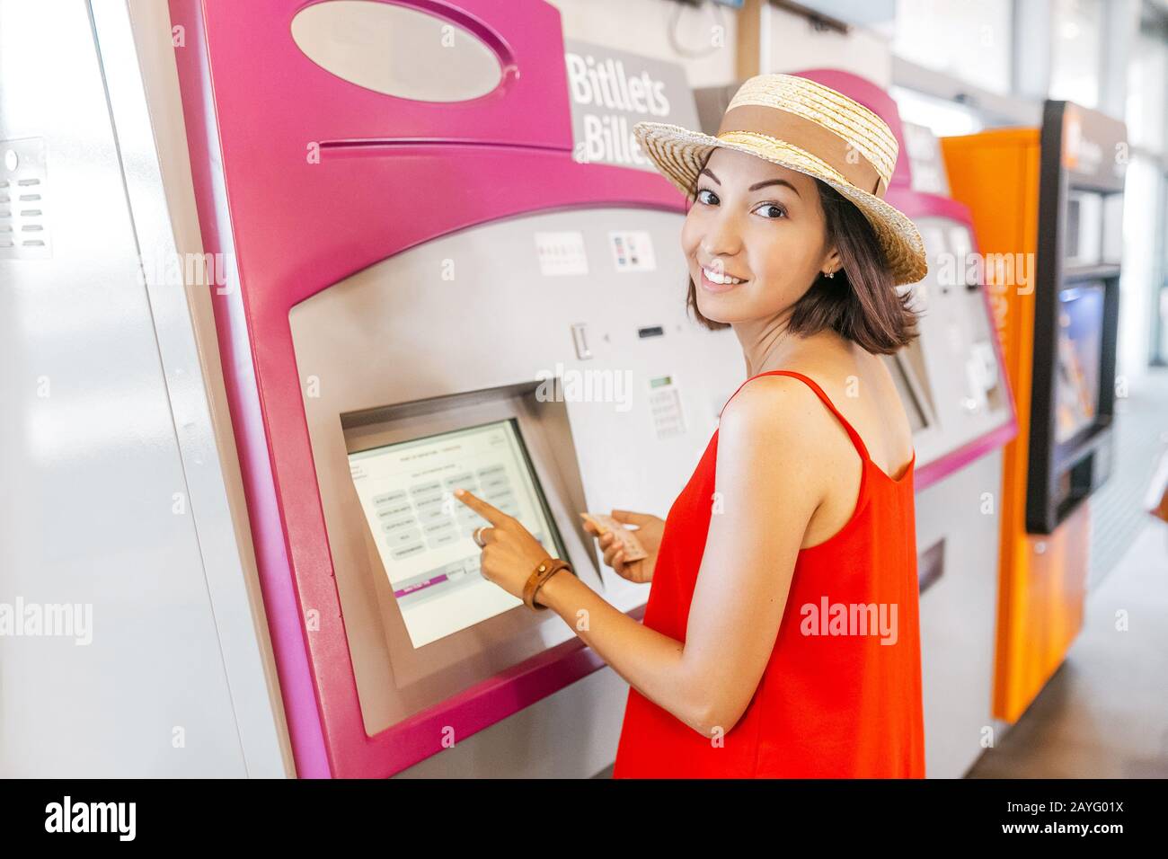 Young woman paying at ticket machine in a metro or railroad station ...
