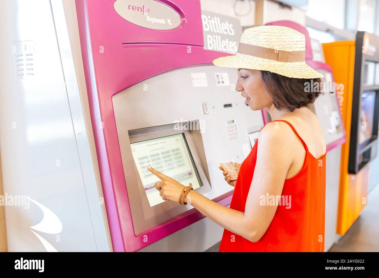 17 JULY 2018, TARRAGONA, SPAIN: Young woman paying at ticket machine in a metro or railroad station Stock Photo