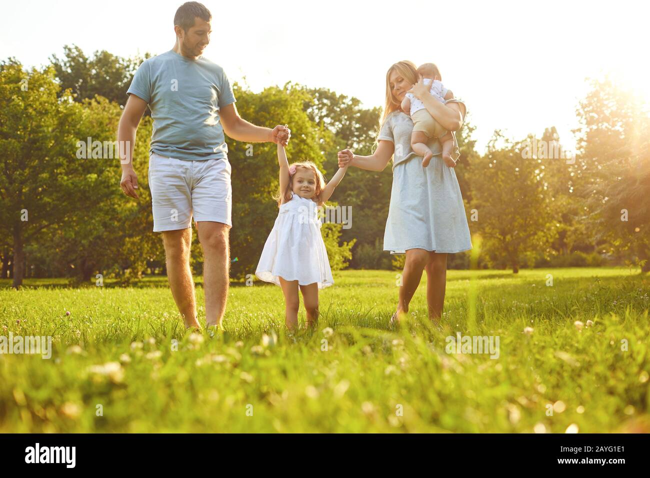 Happy family walking on the grass in the summer park. Children Protection Day. Stock Photo