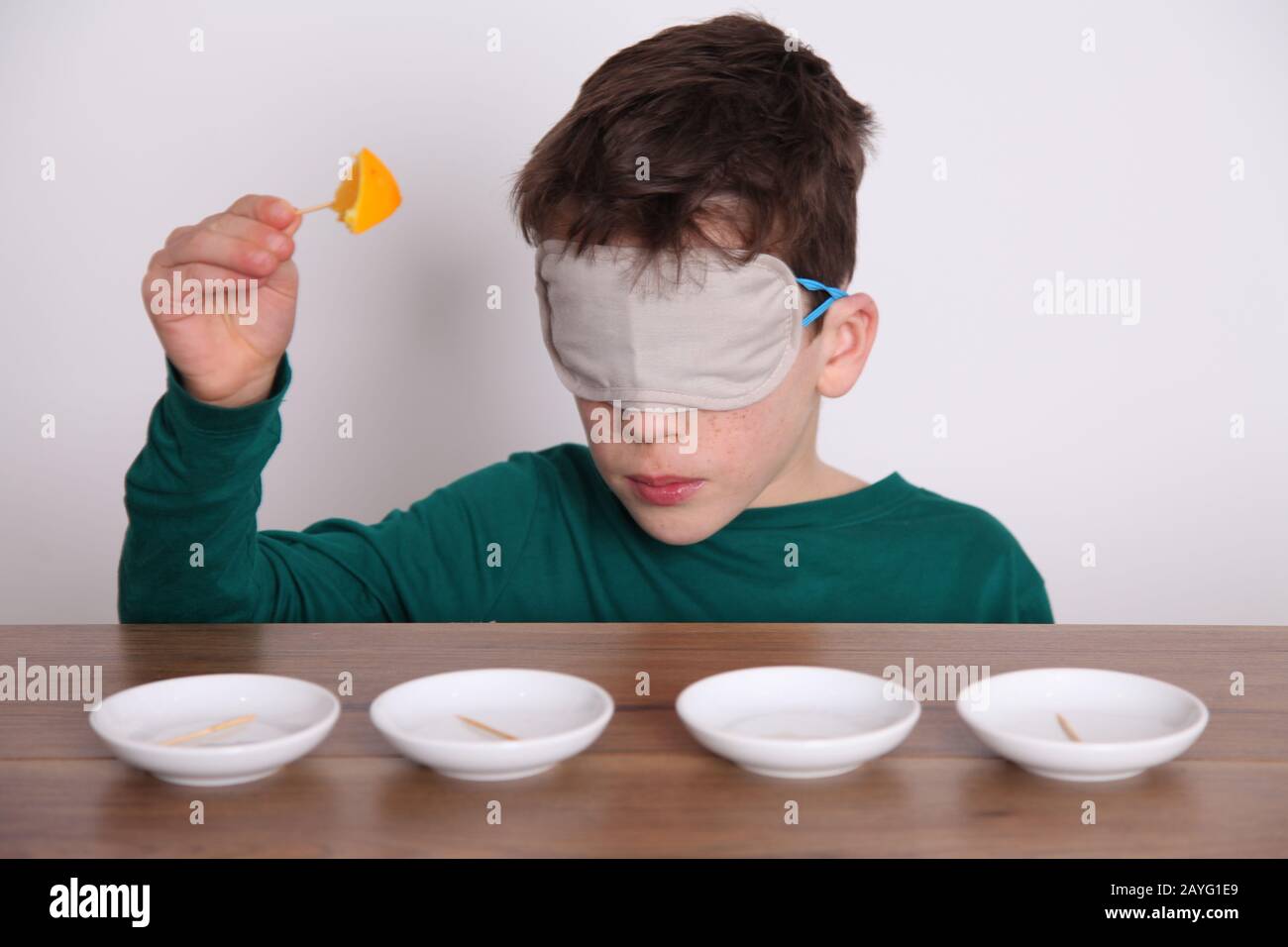 A dark haired boy of 8yrs old takes part in a blindfold taste test
