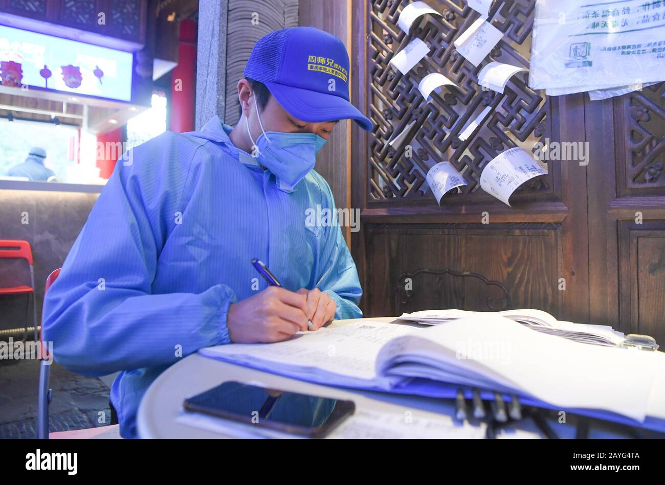 (200215) -- CHONGQING, Feb. 15, 2020 (Xinhua) -- A staff member of a hot pot restaurant records information of takeout food in southwest China's Chongqing Municipality, Feb. 15, 2020. For the prevention and control of novel coronavirus pneumonia, some hot pot restaurants in Chongqing, under the guidance of Chongqing Municipal Commerce Commission and relevant departments, provide consumers with zero-contact hot pot takeout service. Consumers can order food through various platforms such as telephone, WeChat and the Internet. The takeout services were strengthened in the safety of purchase, proc Stock Photo