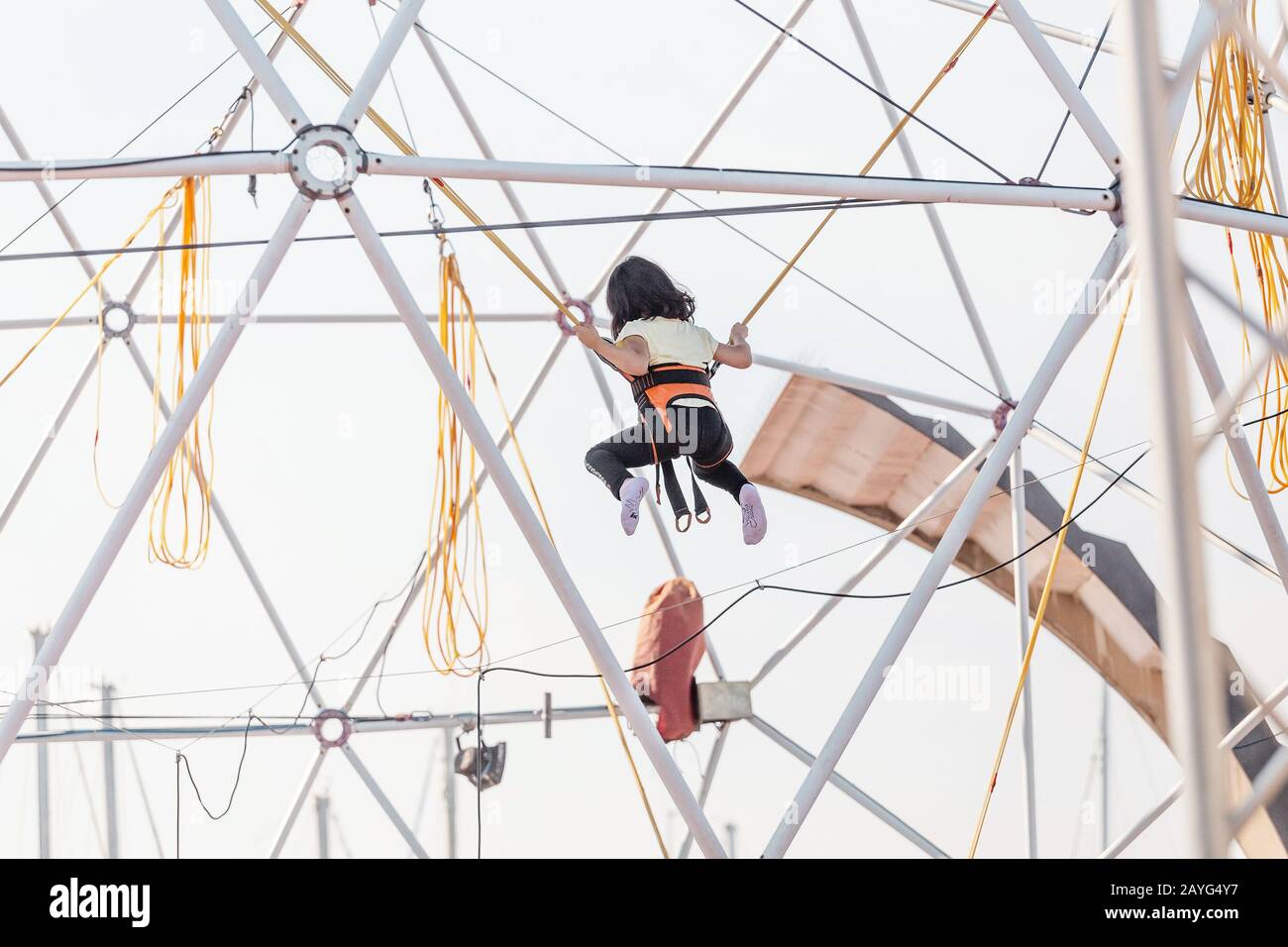 Young boy attached to jumping rope on trampoline Stock Photo Alamy
