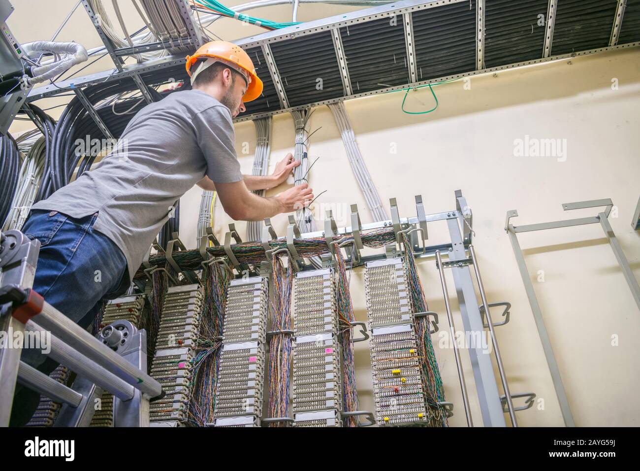 The engineer standing on the stairs works with the switching equipment