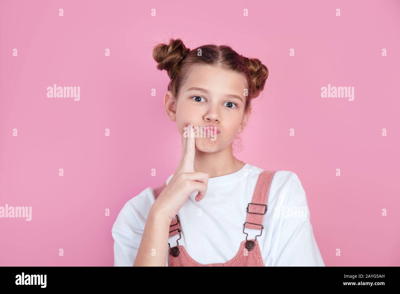 Cute girl puffed cheeks and having a funny face on pink background. Stock Photo