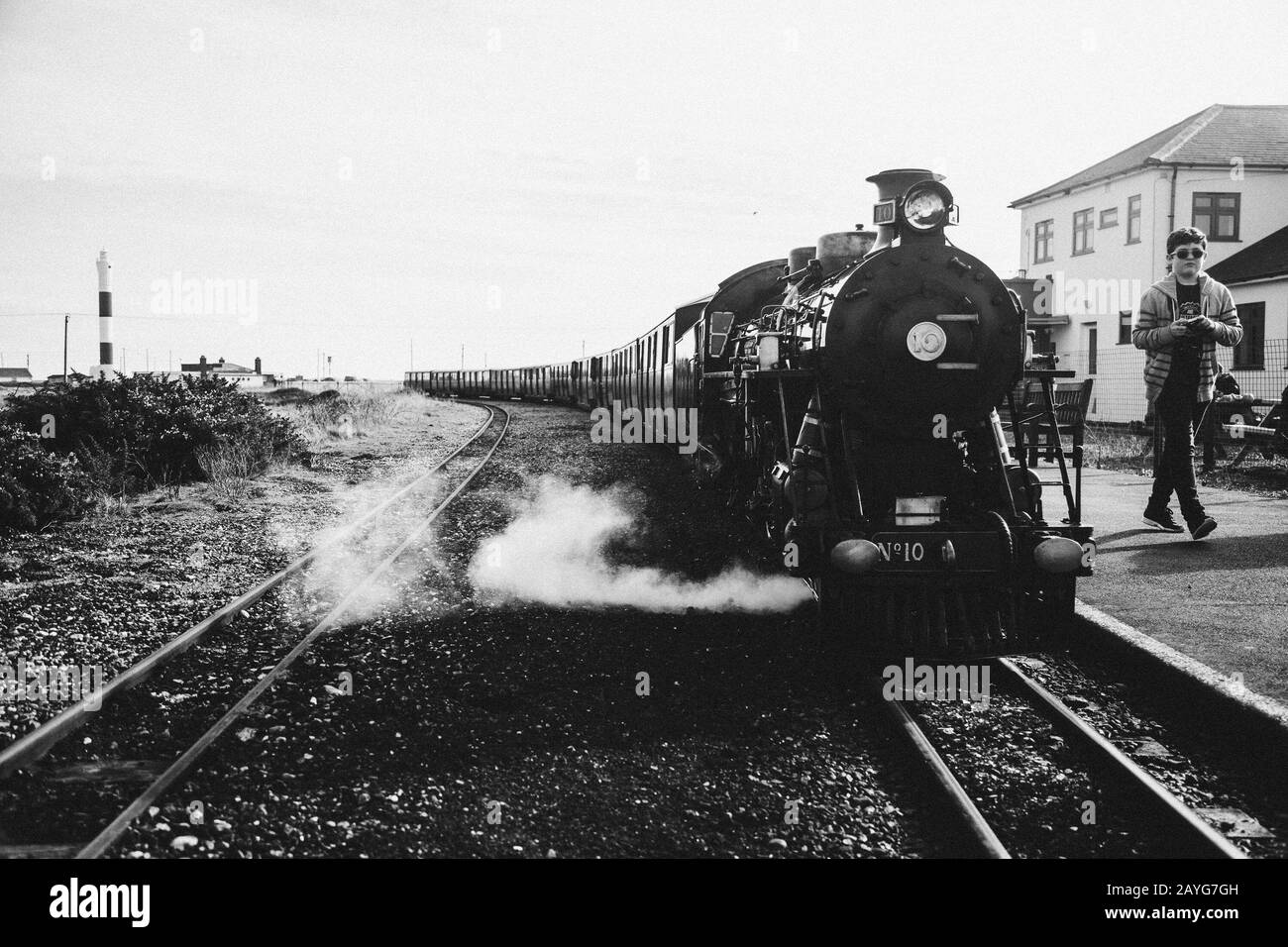 Steam train at Dungeness station with boy walking next to it Stock Photo