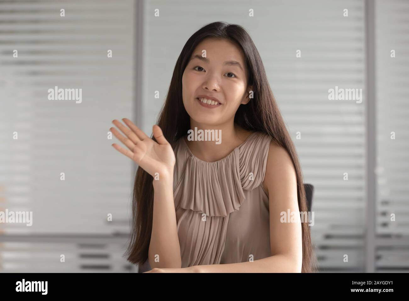 Happy Asian girl waving to camera talking on video call Stock Photo