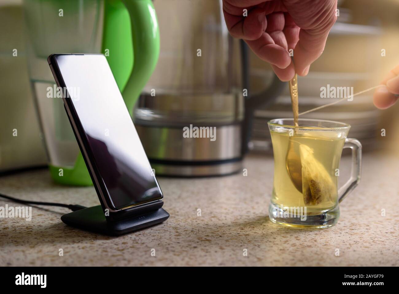 smartphone wireless charging on charging stand next to male hand make ...