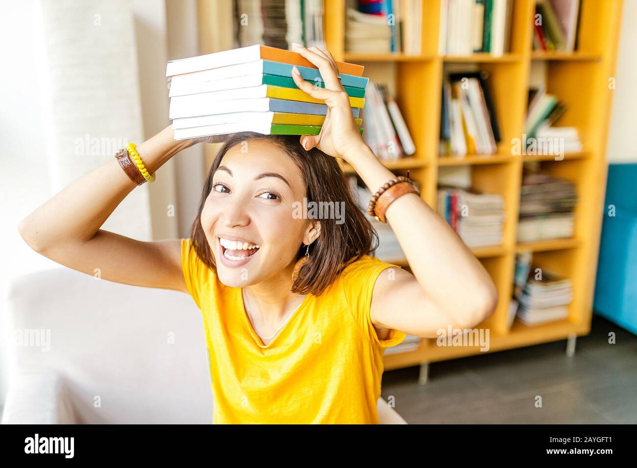 Happy girl student with stack of books in library, education and ...