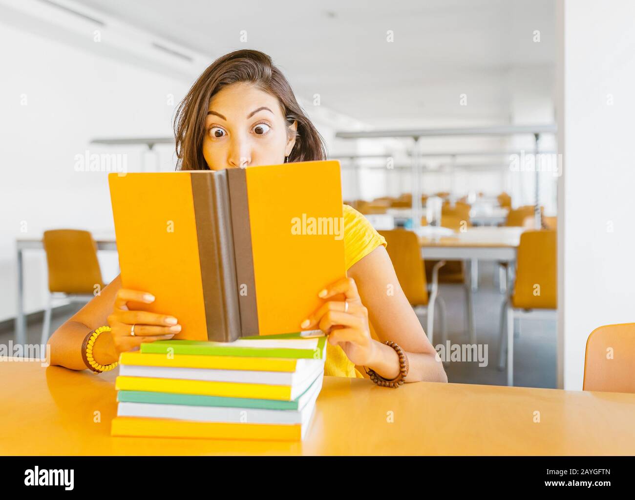 Crazy funny girl reading big book in library Stock Photo - Alamy