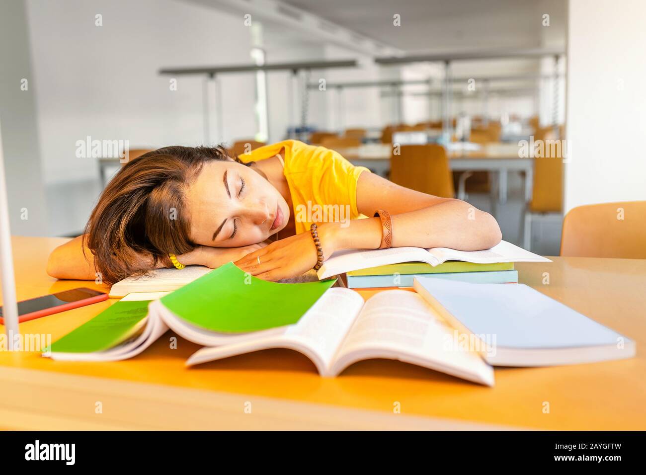 tired student girl sleeping on the stack of books in the library ...