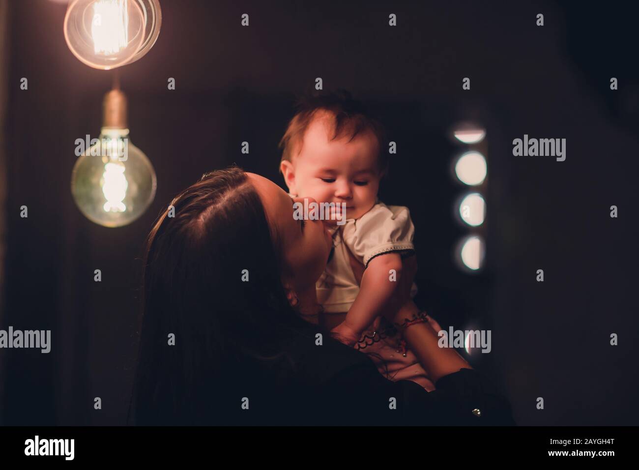 Young mother holding her little baby on studio dark Stock Photo