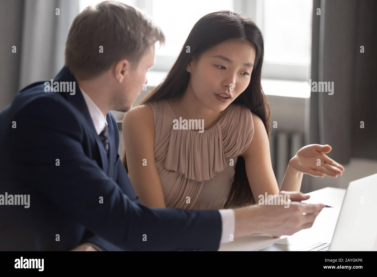 Multiethnic employees discuss project working on laptop in office Stock Photo