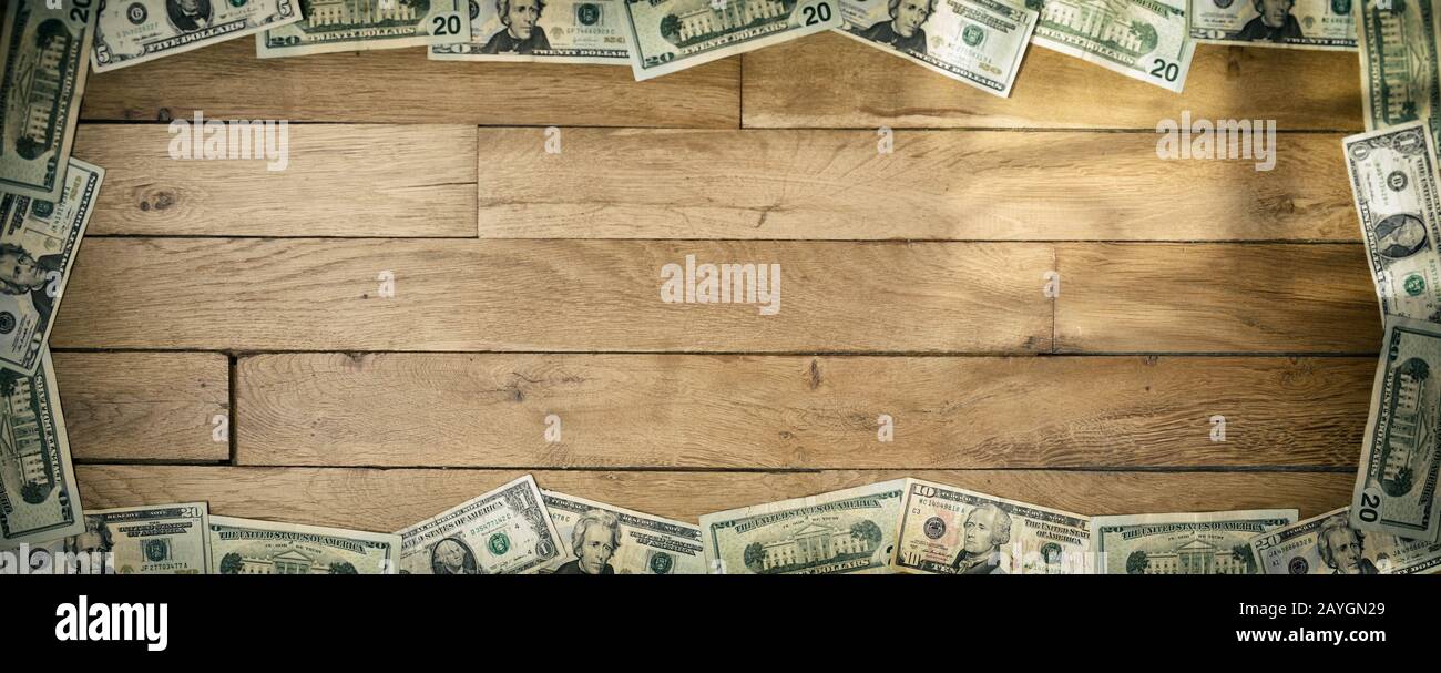 Banner sized background of used dollars banknotes lying on wooden floor. Focus on lower part. Stock Photo