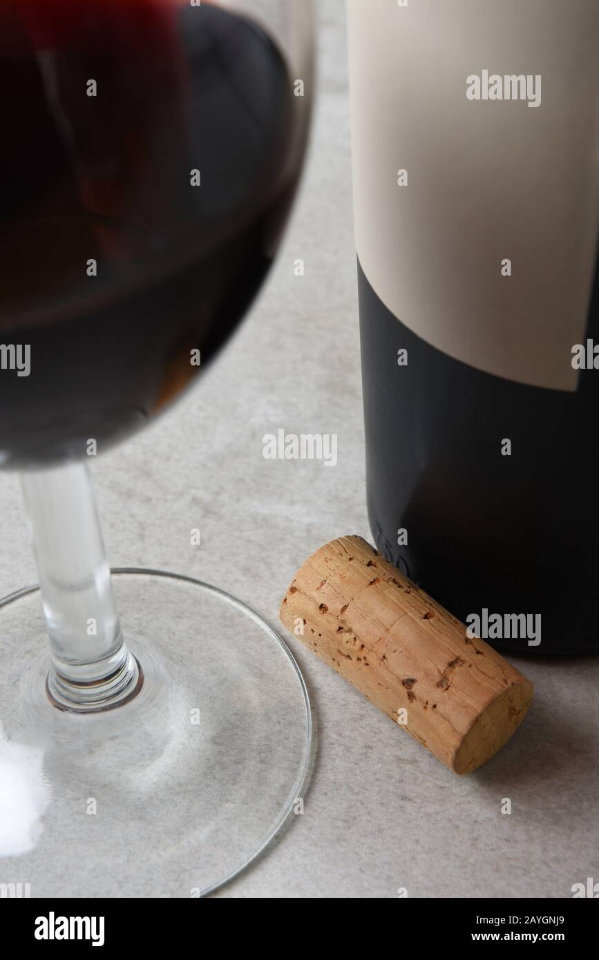 Closeup of a wine cork on a table with wine bottle and wine glass. Focus is on the cork. Stock Photo