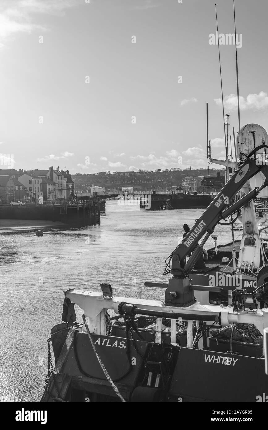 Whitby harbour with a fishing trawler prominent in the foreground,  The town lies beyond with buildings lining the waterfront and and a connecting bri Stock Photo