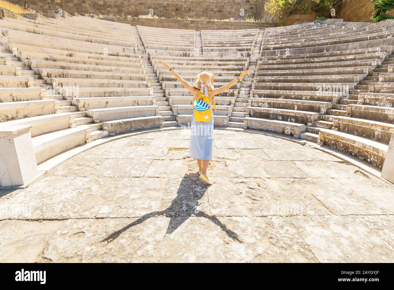 Asian girl tourist traveling in the ruins of an ancient Acropolis or the amphitheatre with a Greek flag. Active young travelers and students concept Stock Photo