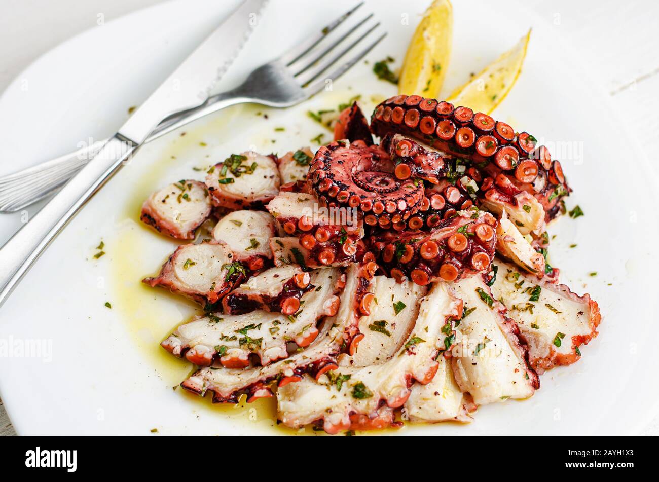Delicious octopus carpaccio with dressing on white plate. Seafood delicacy Stock Photo