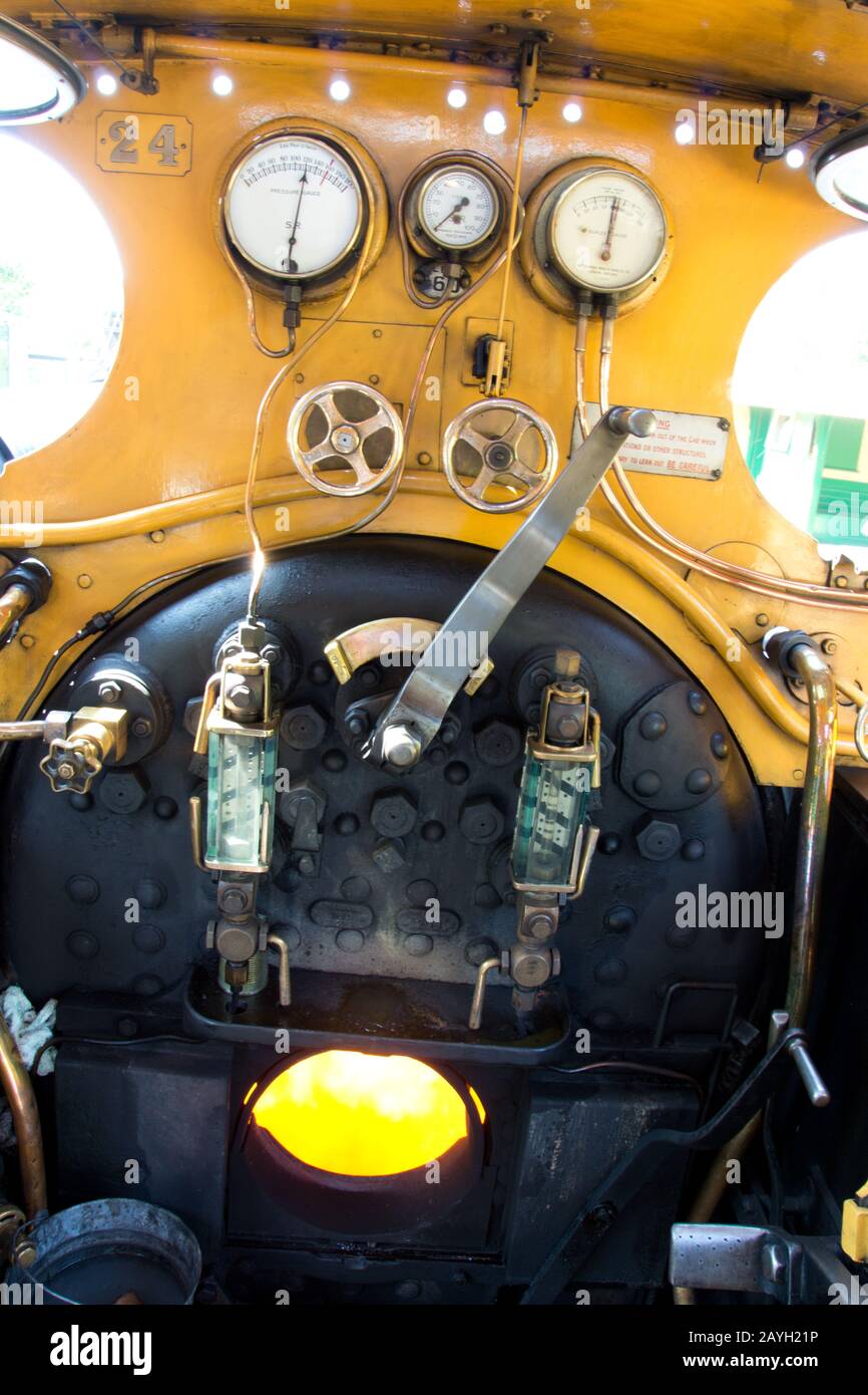 the cab or footplate of an old steam locomotive showing the controls and the burning fire Stock Photo