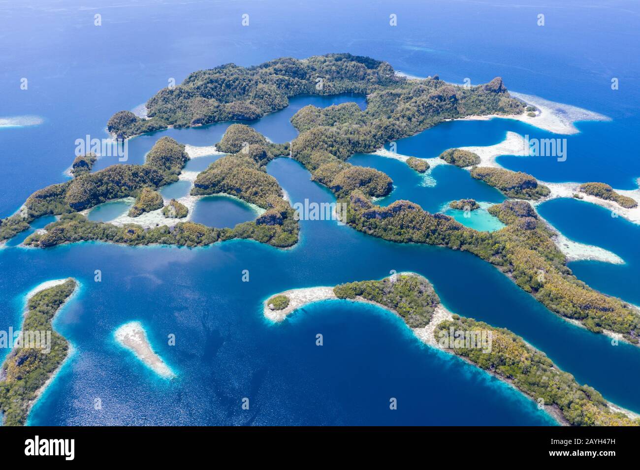 Forest-covered limestone islands rise from the seascape in Raja Ampat, Indonesia. This remote region is known for its great marine biodiversity. Stock Photo