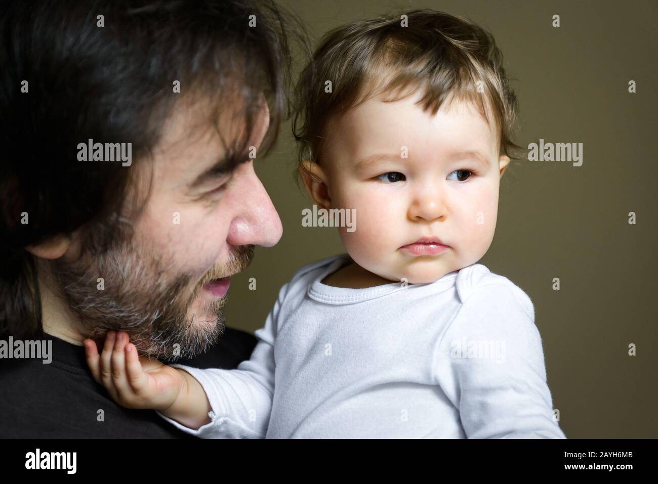 Baby sitting on hands of his happy father at home. One-year child. Stock Photo