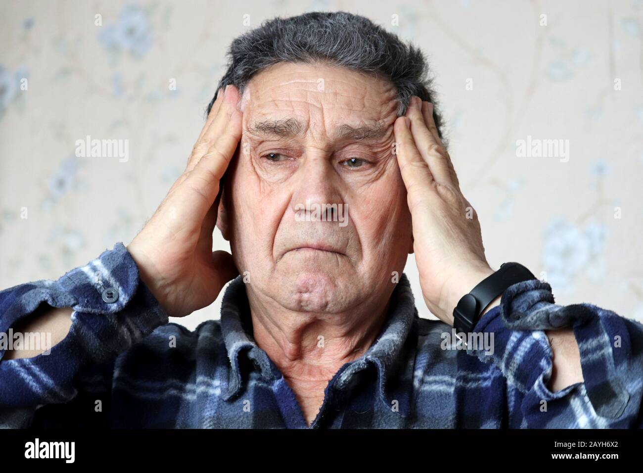 Elderly man massages the temples with her hands. Portrait of upset male, concept of headache, high blood pressure, mental activity in old age, memory Stock Photo