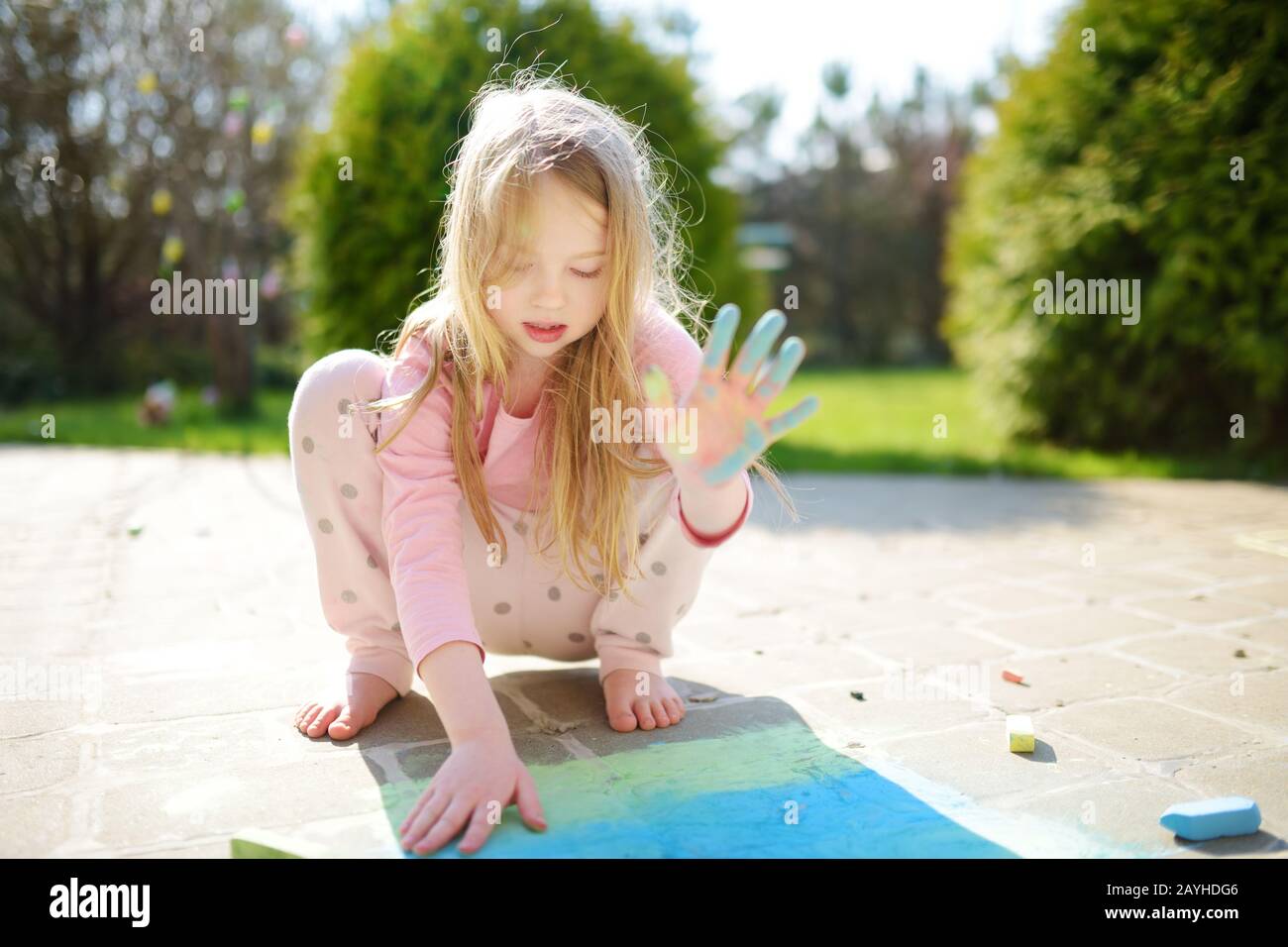 Cute Little Girl Drawing With Colorful Chalks On A Sidewalk