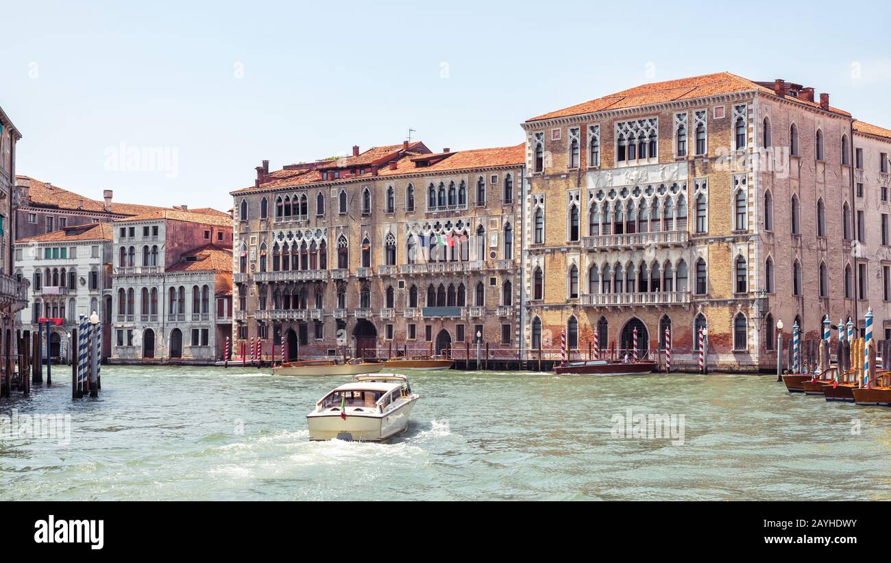 Motor boat sails on the Grand Canal in Venice, Italy. Romantic water trip in Venice. Panoramic view of Venice with beautiful old houses. Sunny panoram Stock Photo