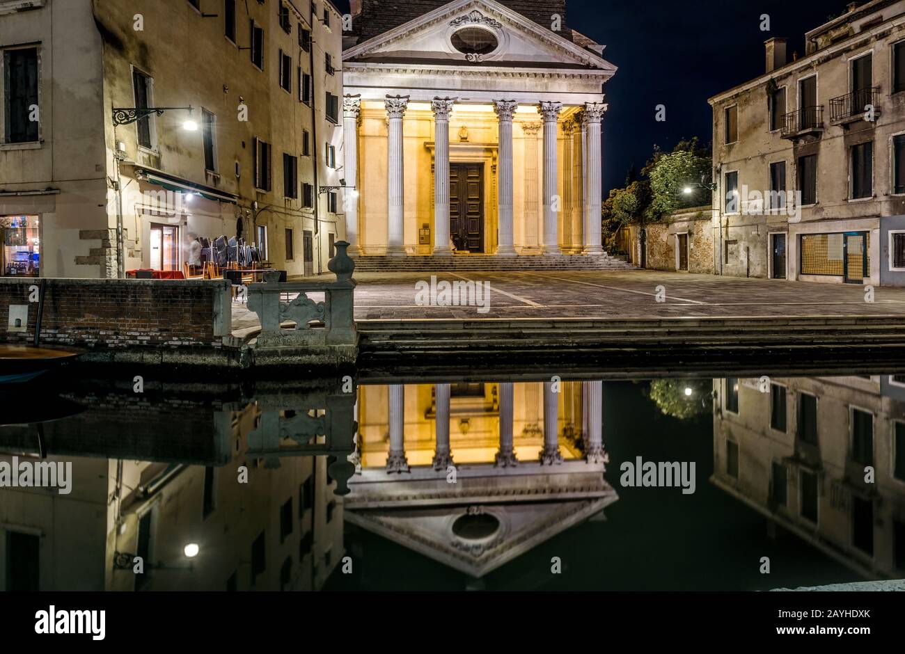 Venice at night, Italy. Panorama of a deserted street in evening. Illuminated old church with reflection in a water canal. Romantic walk through night Stock Photo