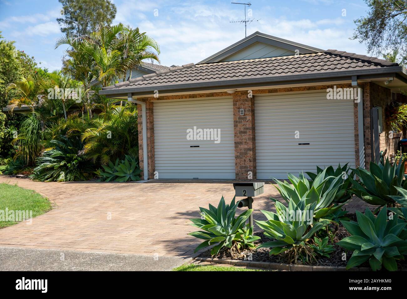 Australian home and garden with double garage plants and grass in the