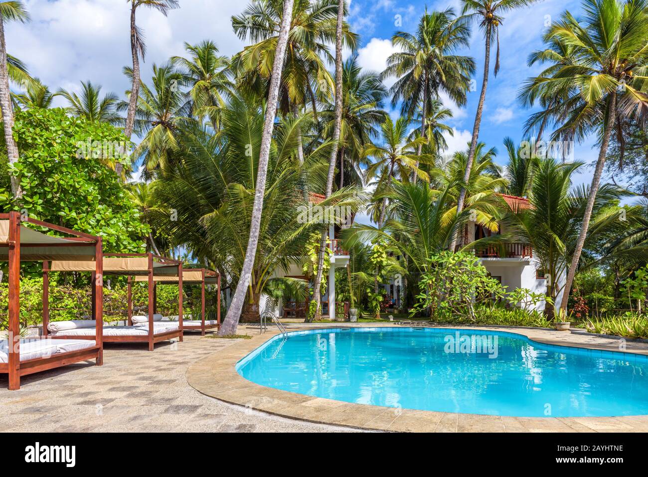 Tangalle, Sri Lanka - Nov 4, 2017: Swimming pool and beach beds in a tropical hotel. Panorama of the pool with blue water in tropics. Idyllic resort a Stock Photo