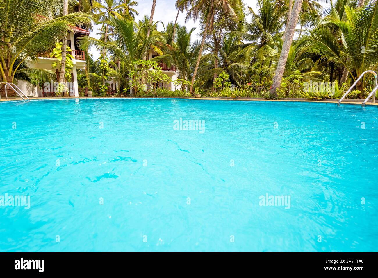 Swimming pool in tropical hotel. Scenic pool with blue water in a tropic. Idyllic place to relax. Clean water in pool for background. Panoramic view o Stock Photo