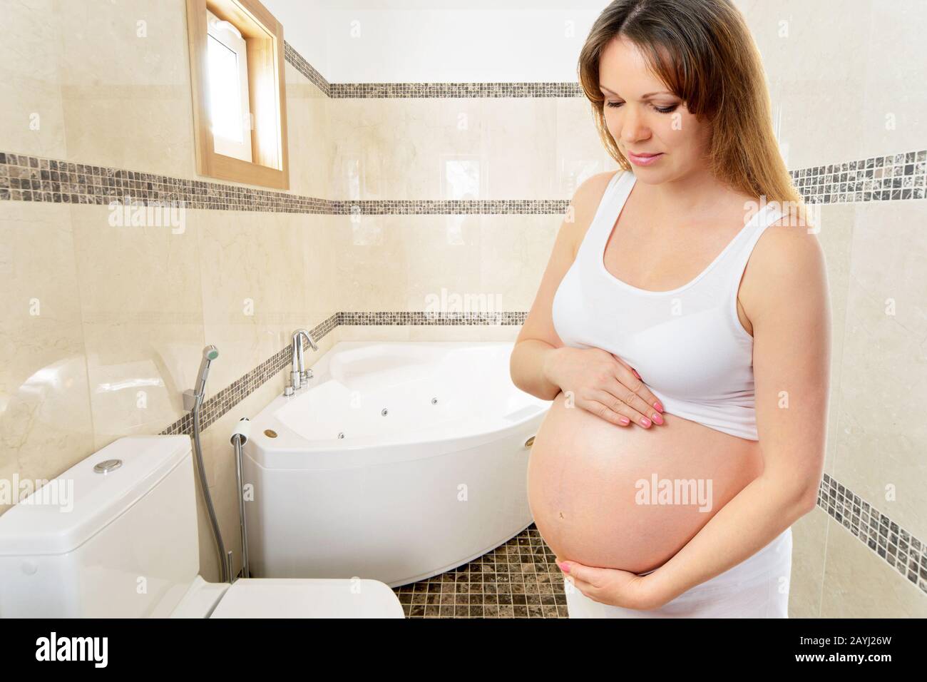 A cute pregnant woman in the bathroom at home Stock Photo