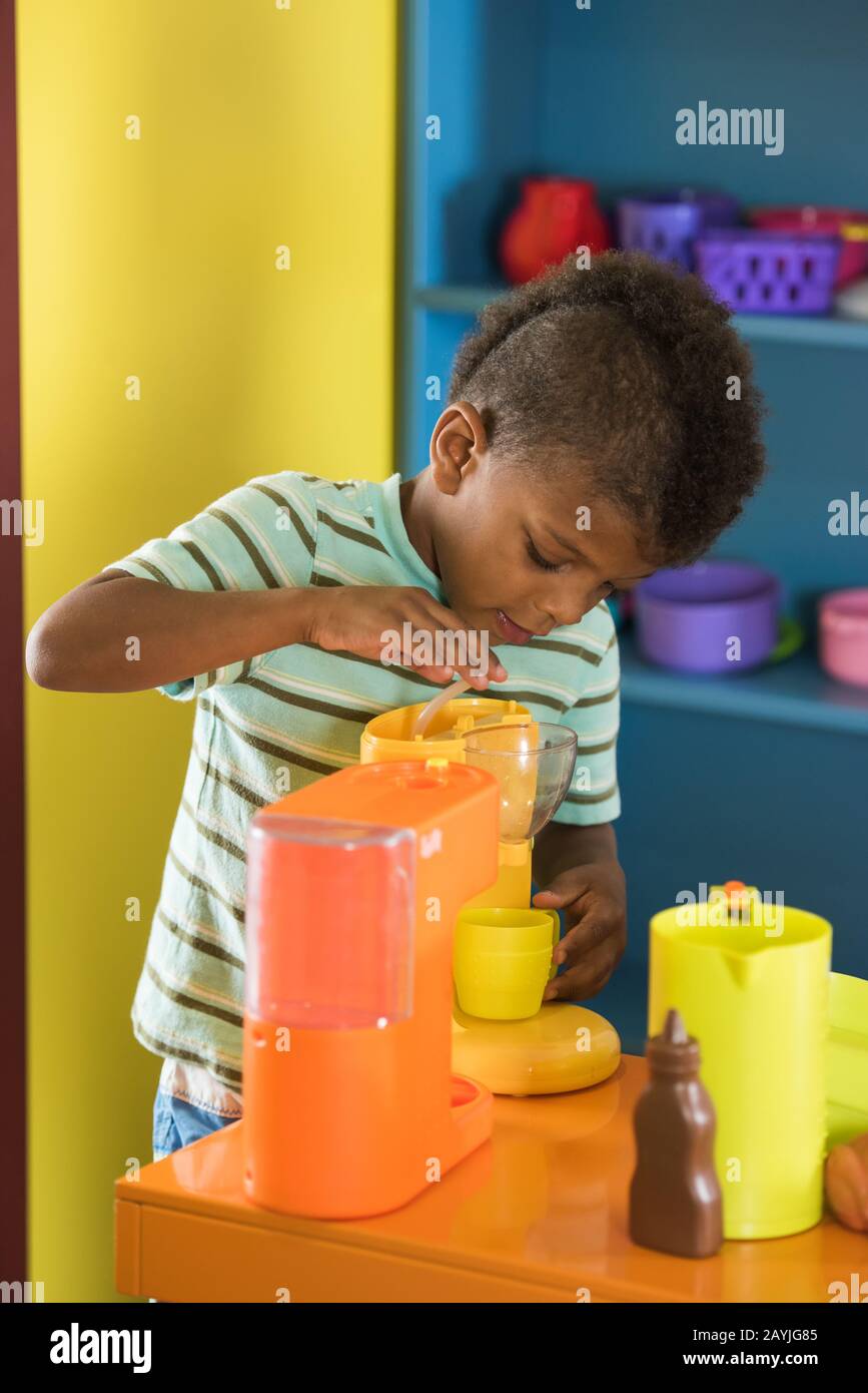 Little boy playing with toy in toy kitchen Stock Photo - Alamy