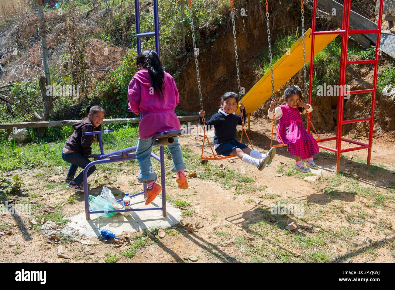 Girls from the kindergarten class on the swing set and teeter totter seesaw of playground of the school in the Mixtec village of San Juan Contreras ne Stock Photo