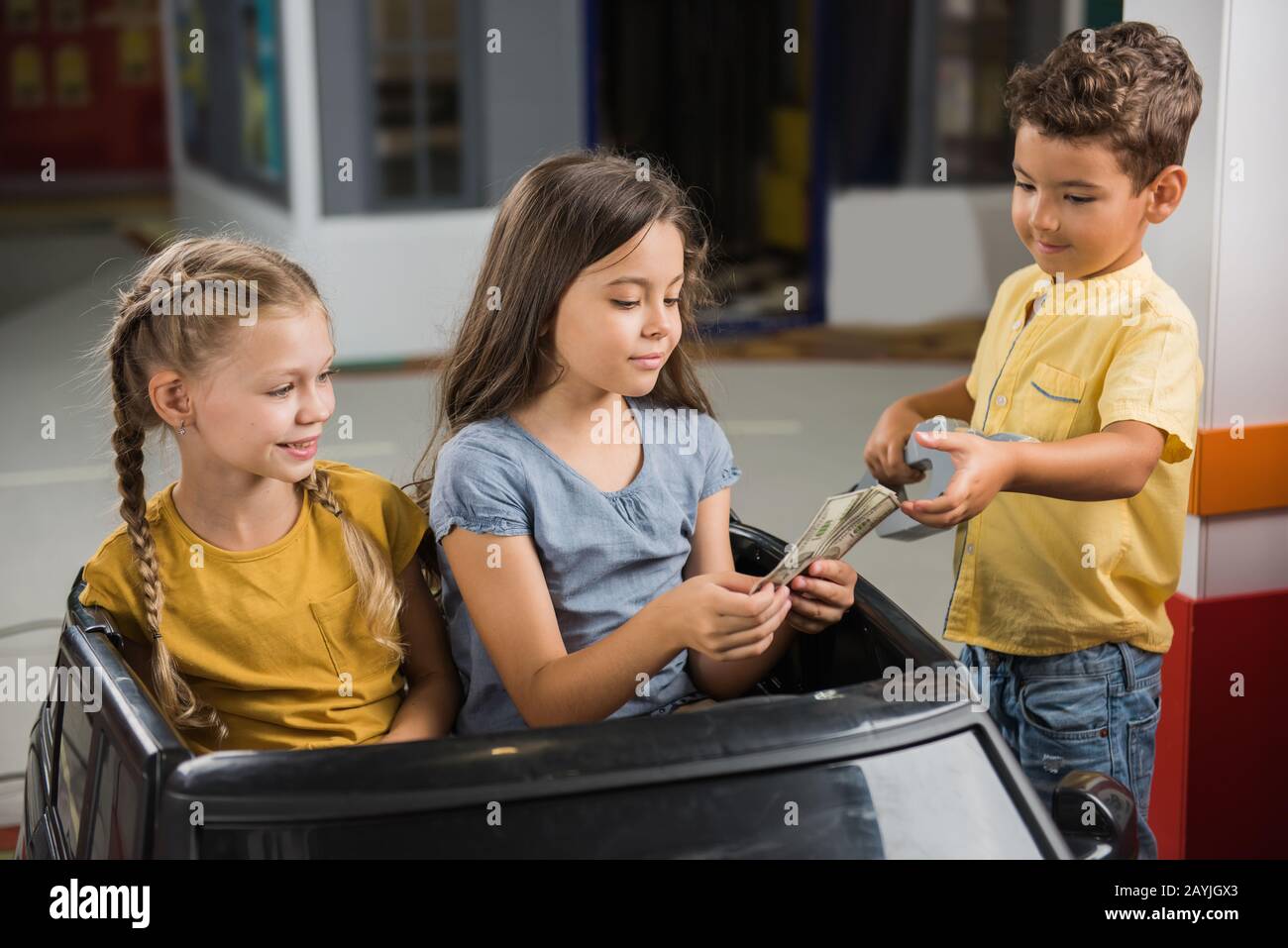 Little girls sitting in toy car at entertainment center Stock Photo - Alamy