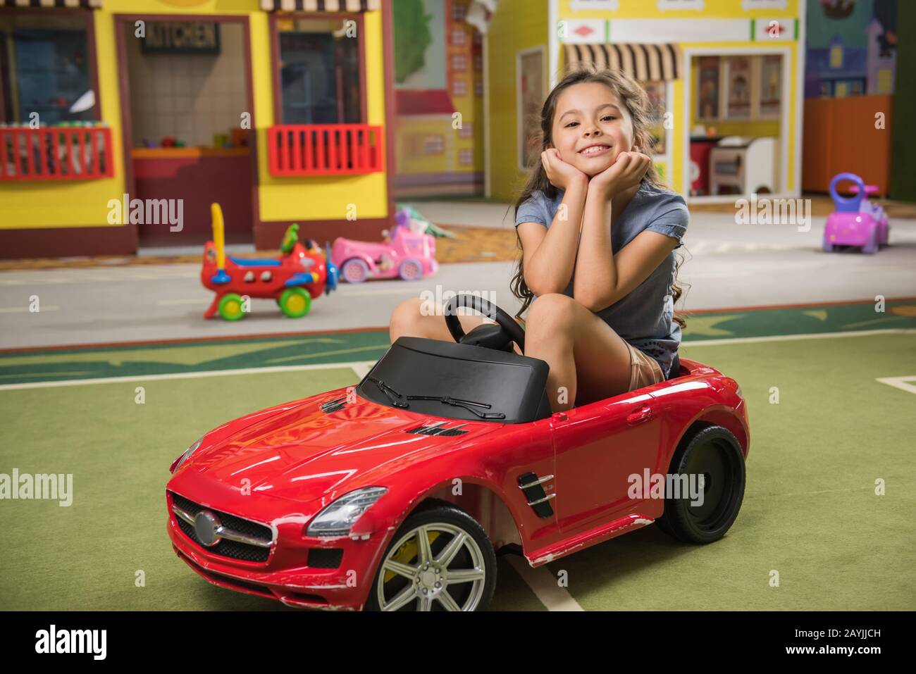 Adorable kid in toy car smiling at camera in play center Stock Photo Alamy
