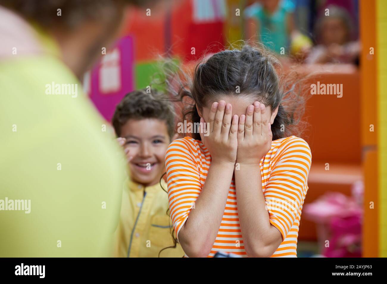 Kid girl covering her face with both hands Stock Photo - Alamy