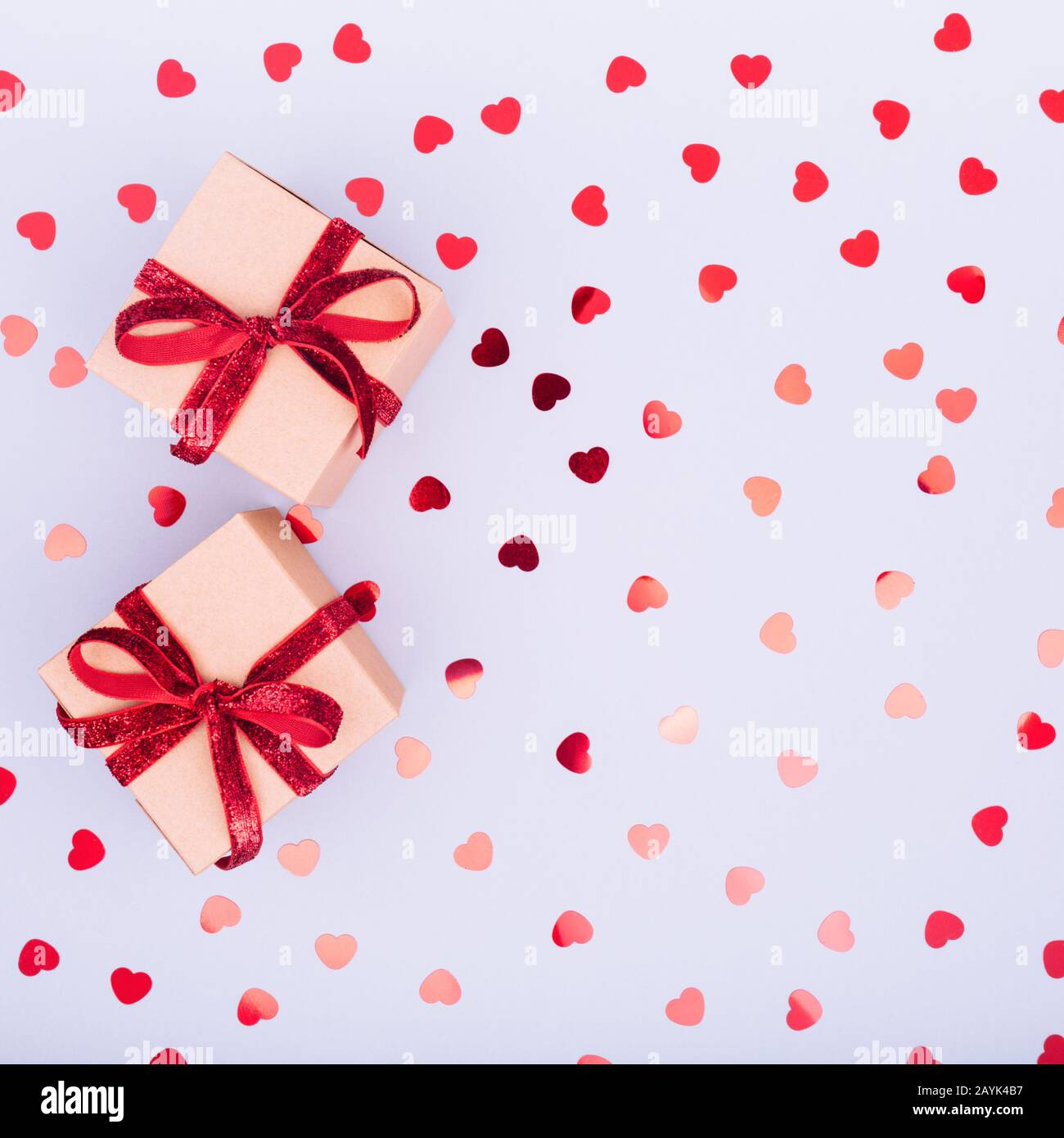 Craft box with red ribbon bow and glitter heart confetti. Valentine day ...