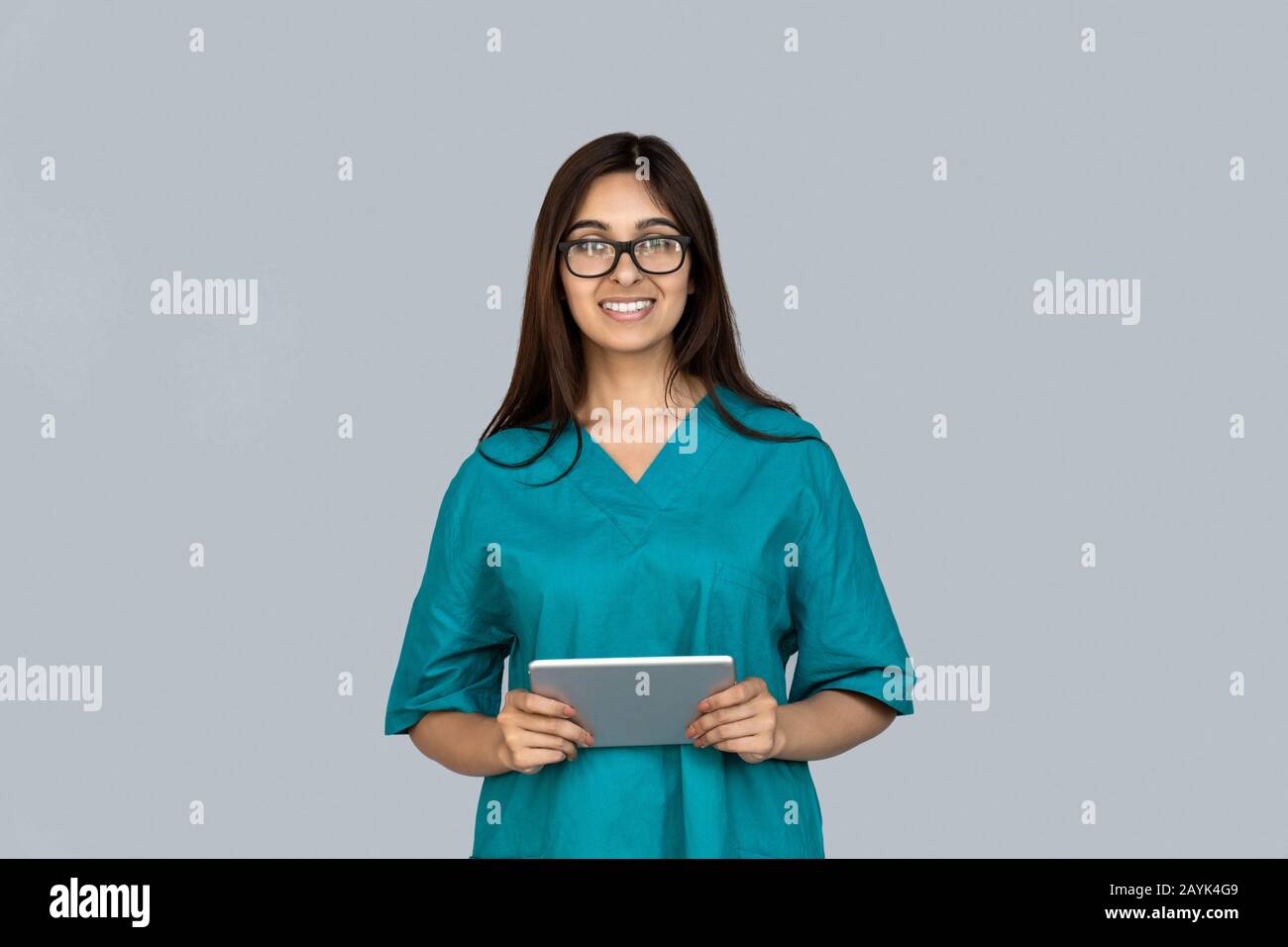 Happy young adult indian woman in doctor uniform holding tablet computer Stock Photo