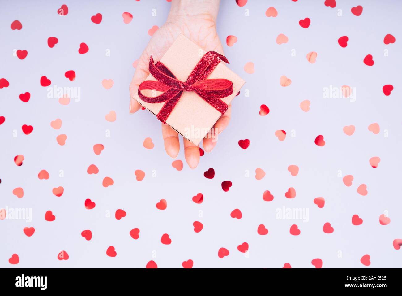 Craft box with red ribbon bow in female hand. Valentine day concept ...