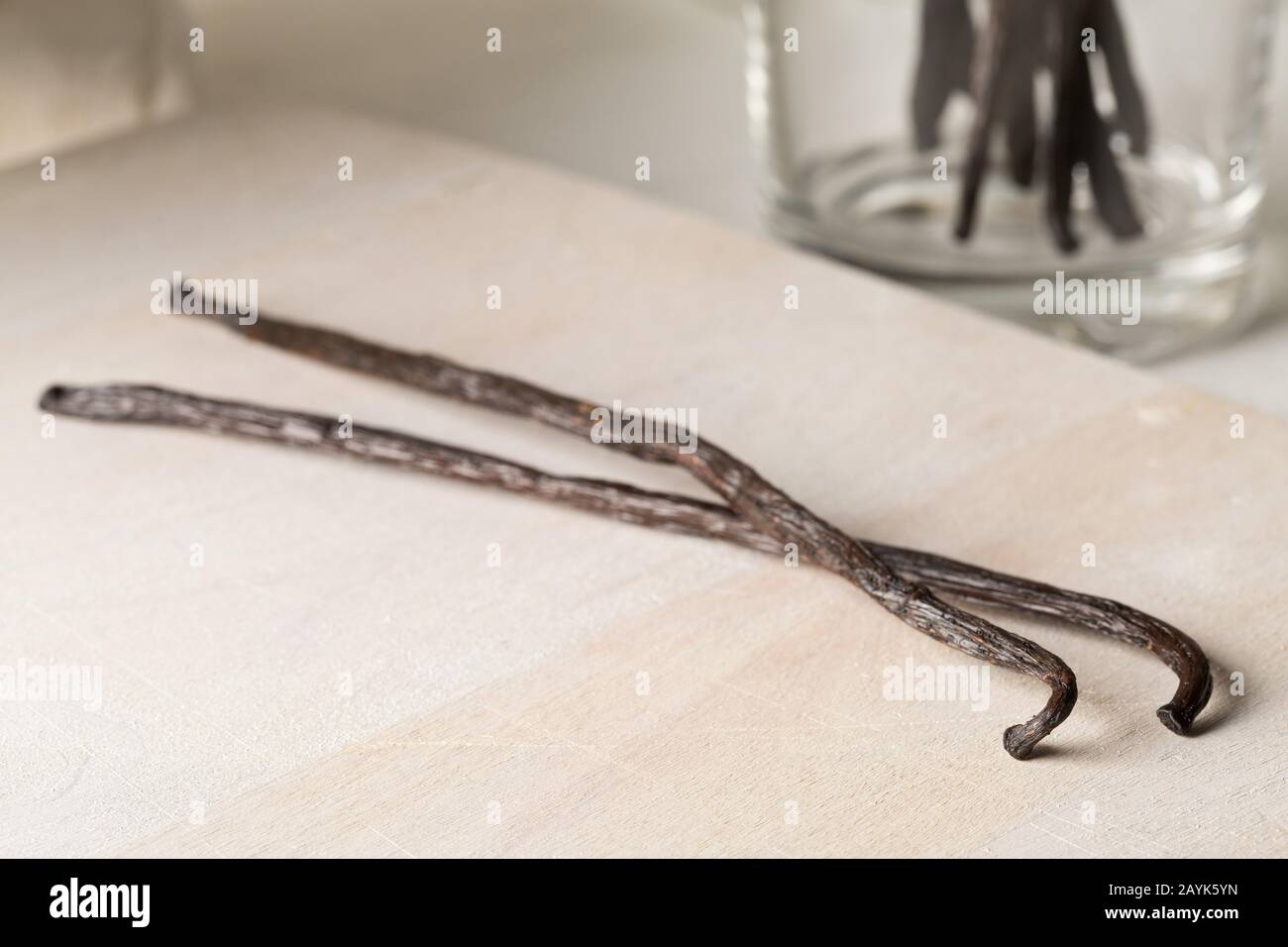 Bundle of dried bourbon vanilla beans or pods on wooden cutting board on white kitchen background - selective focus Stock Photo