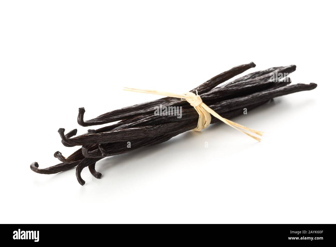 Bundle of tied, dried bourbon vanilla beans or pods over white background - selective focus Stock Photo
