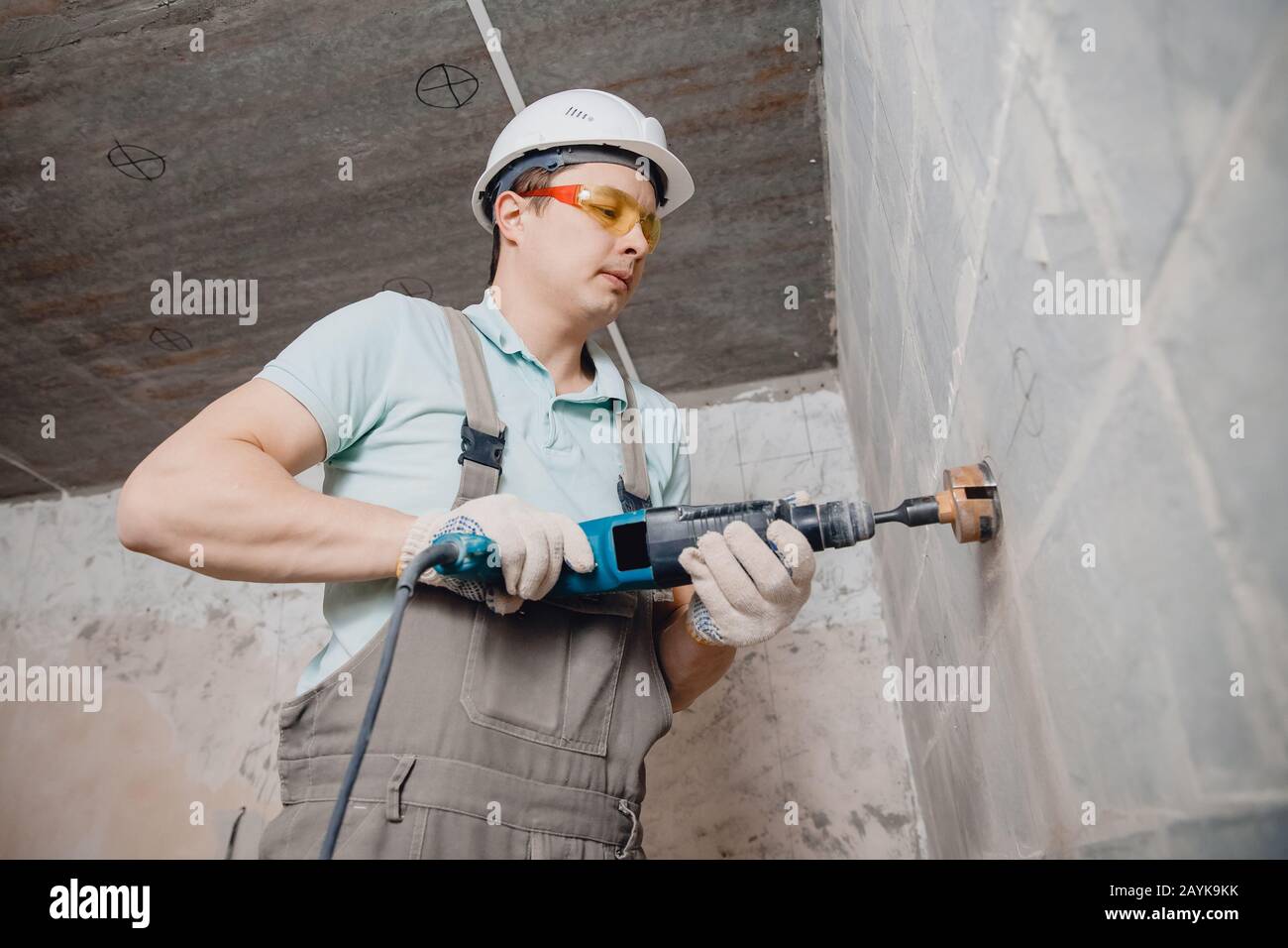 Builder worker pneumatic hammer drills hole in concrete brick wall with diamond crown for