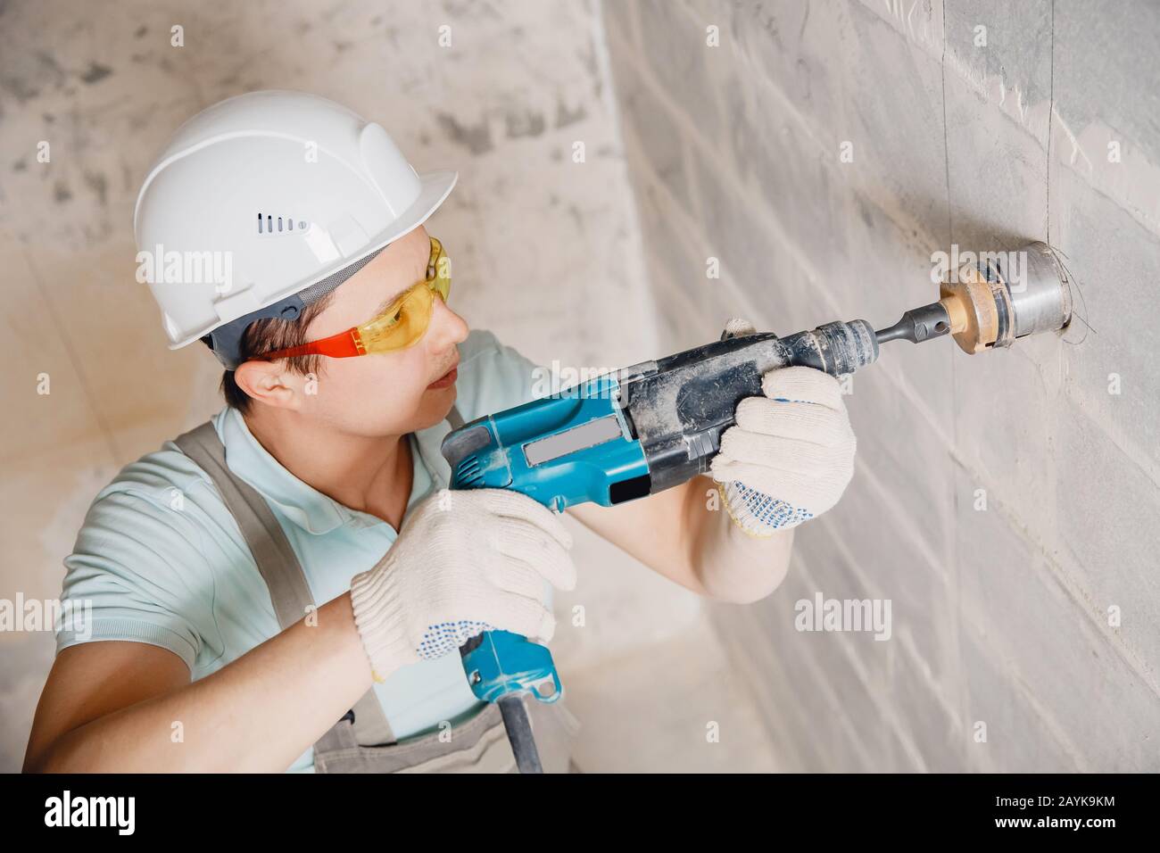 Builder worker pneumatic hammer drills hole in concrete brick wall with