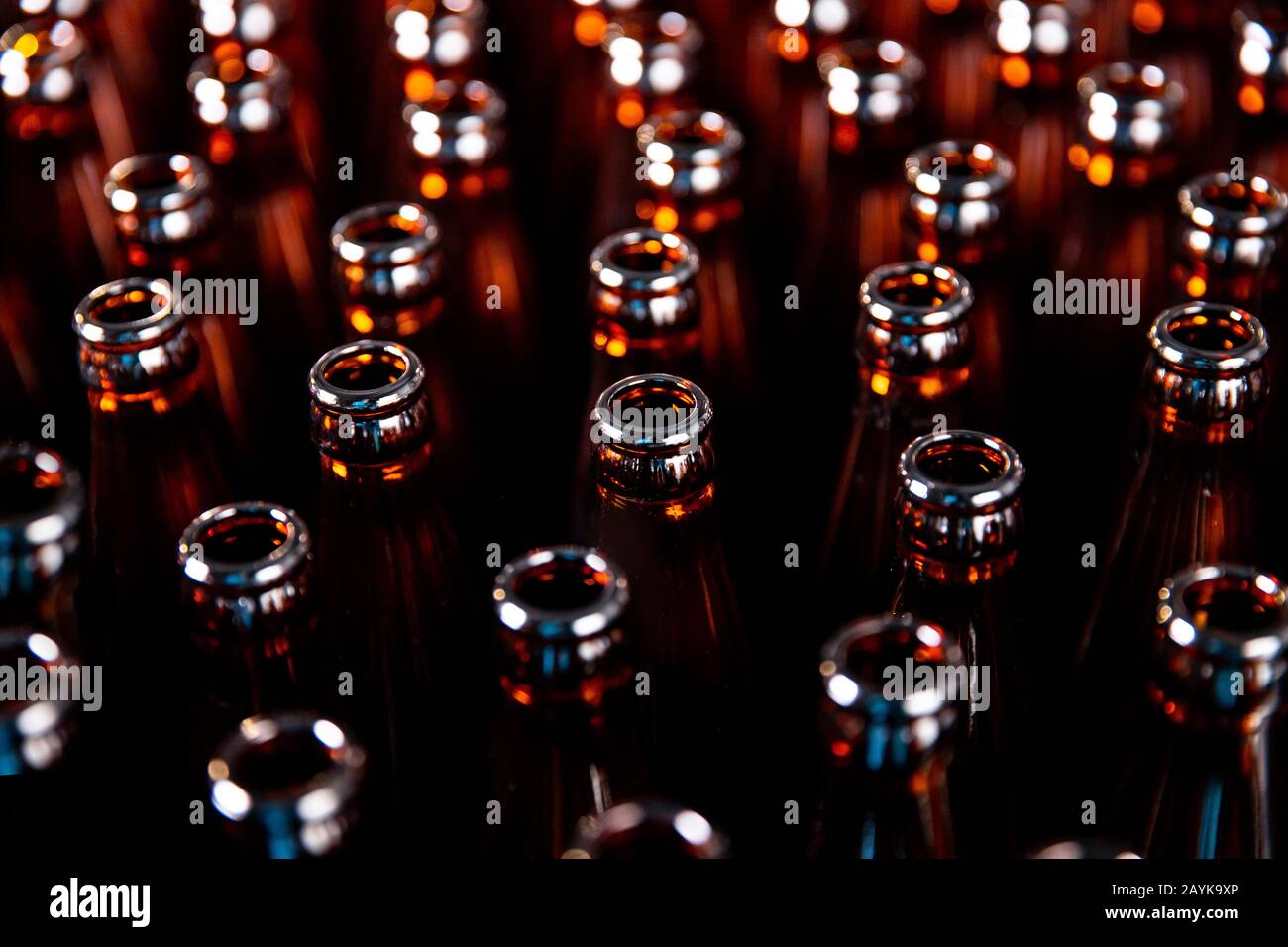 Glass bottles of beer on dark background with sun light. Concept brewery plant production line