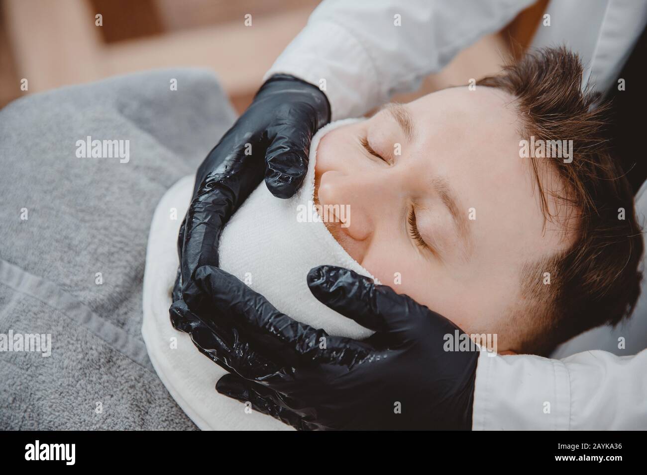 Barber steam face skin of man with hot towel before royal shave in