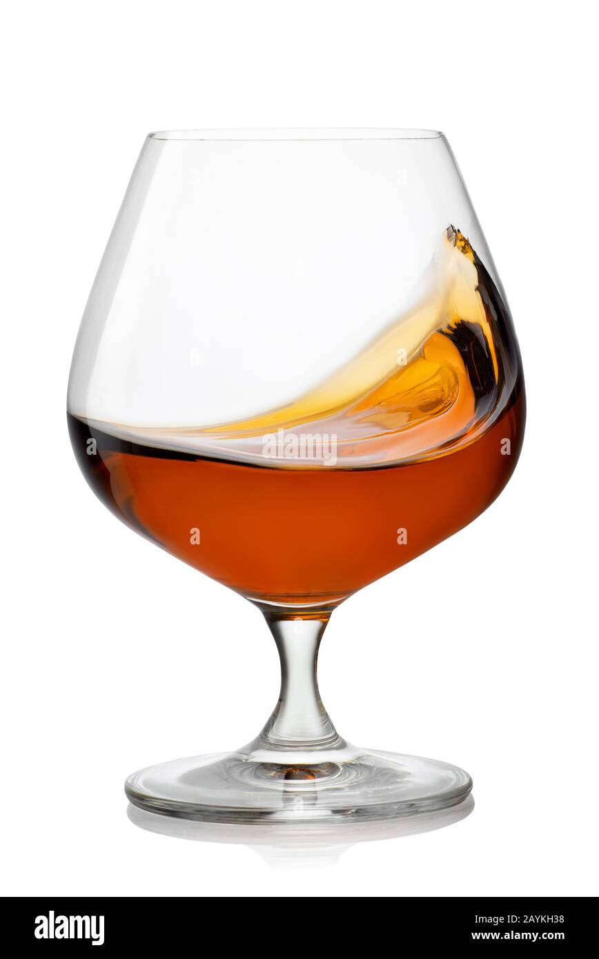splash of brandy in snifter glass isolated on white background Stock
