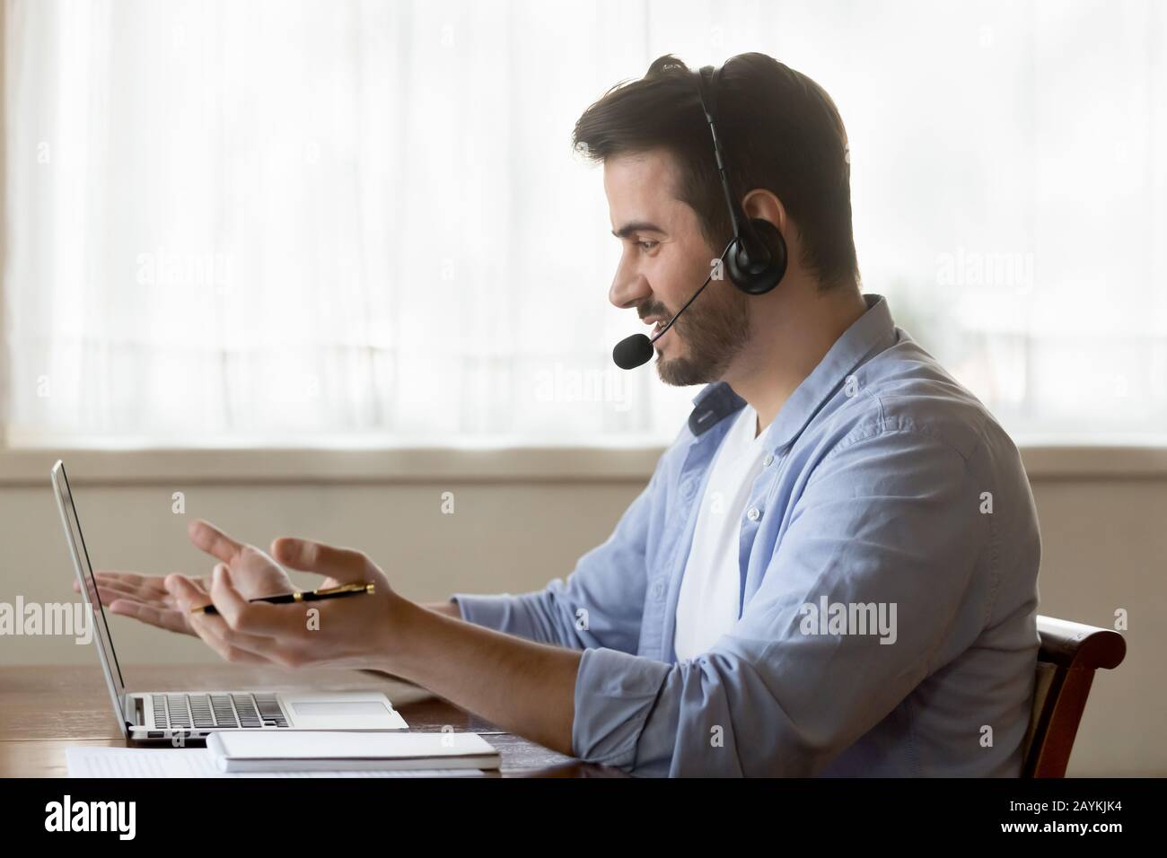 Male worker in headset consult clients on laptop online Stock Photo