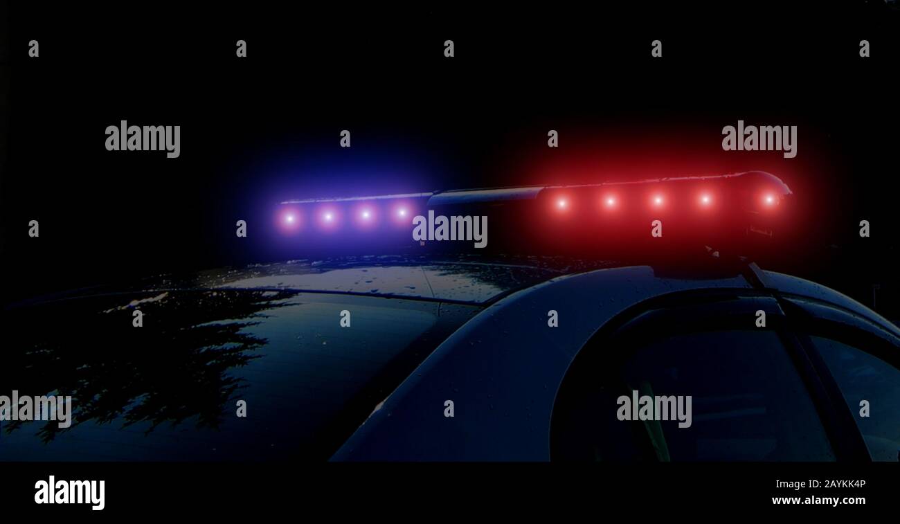 Blurred defocused silhouette of road police patrol car on the street of city at night. Flashing red and blue police car led lights in night time. The Stock Photo